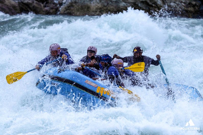 A rafting crew paddling through whitewater rapids