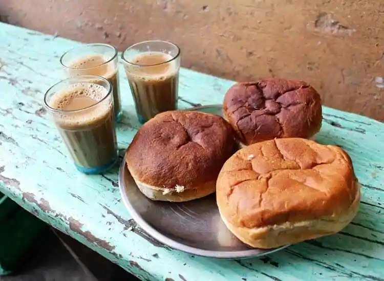 Glasses of chai beside buns at a roadside stall